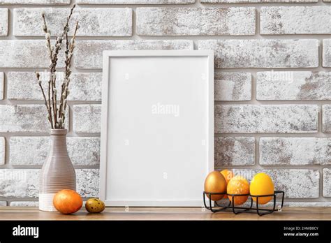 Composition With Photo Frame Easter Eggs And Pussy Willow Branches On Table Near Light Brick