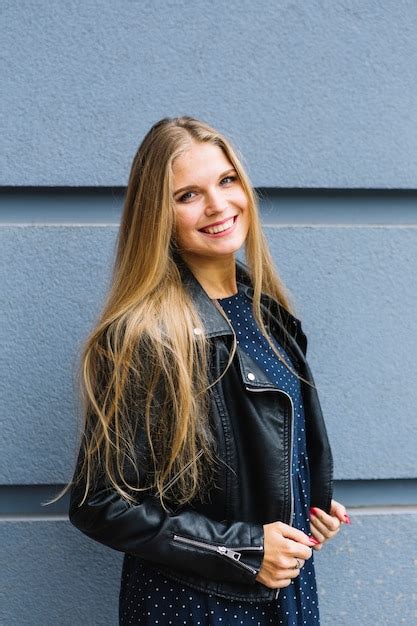 Blonde Jeune Femme Portant Une Veste En Cuir Noir Debout Devant Le Mur Photo Gratuite
