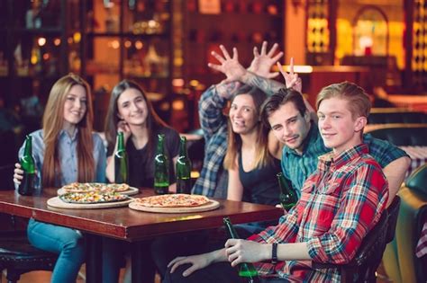 Amigos tomando una copa en un bar están sentados en una mesa de madera