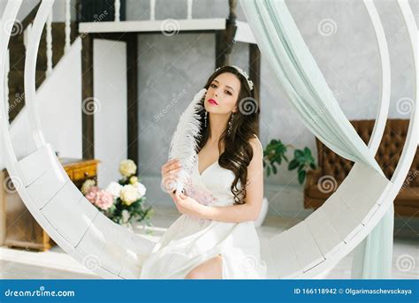 A Beautiful Brunette Bride Holds A Pen In Her Hands And Touches Herself On The Face With A Pen