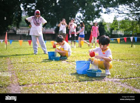 Children Compete In Fill The Bottle Game During Their Kindergarten