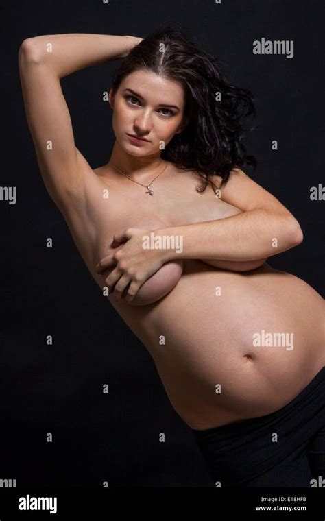 Pregnant Woman Posing Nude Cupping Her Large Swollen Abdomen Tenderly With Her Hand While
