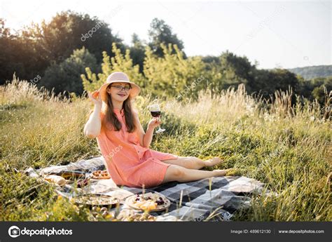 Gorgeous Woman In Orange Dress And Hat Holding Wine Glass Having Picnic