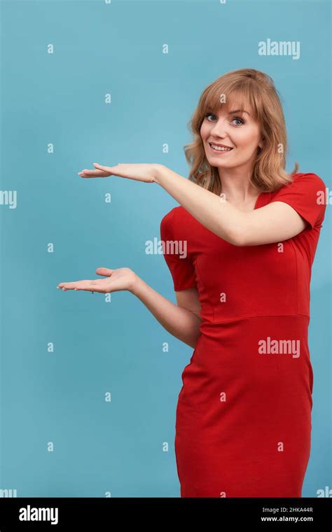 Jeune belle femme blonde portant une élégante robe rouge faisant un cadre avec ses mains sur un