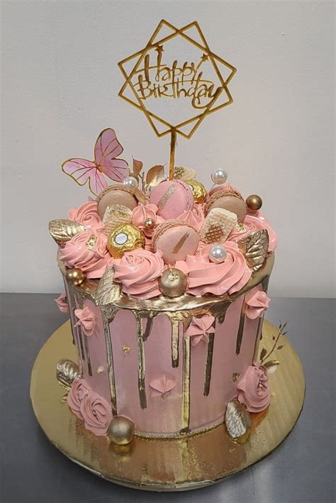 A Birthday Cake With Pink Frosting And Gold Decorations