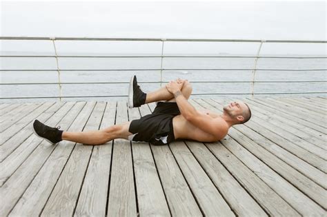 Premium Photo Fitness Man With A Naked Torso Doing Leg Stretching While Lying On Wooden Plank