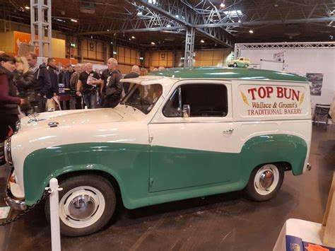 An Old Green And White Truck Parked Inside Of A Building With People