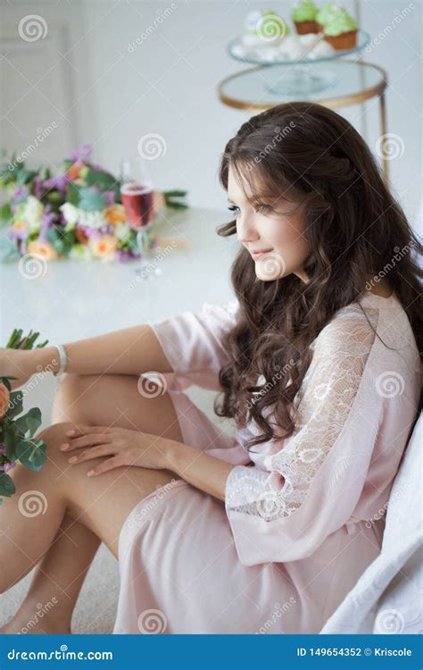 Sch Ner Junger Brunette In Einem Seidenhemd Sitzt Nahe Dem Bett Mit Einem Blumenstrau Von