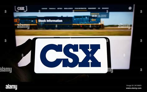 Person Holding Smartphone With Logo Of Us Transportation Company Csx