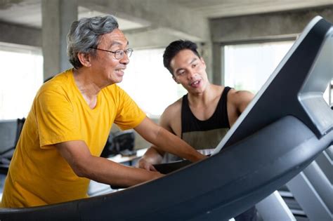 Premium Photo Trainer Assisting Man In Exercising On Treadmill At Gym