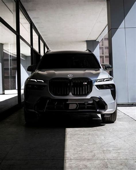 The Front End Of A White Bmw Suv Parked In A Parking Garage Next To A