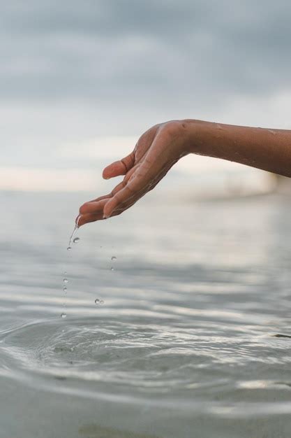 Mano Cortada De Una Mujer Jugando Con Agua En El Mar Foto Premium