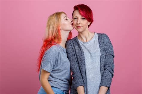 Two Lesbian Girls One Kisses Another On The Cheek On A Pink Background Stock Photo Image Of