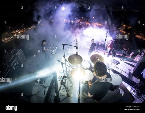 Rock Band Performing On Outdoor Stage With Purple Lights And Fog As