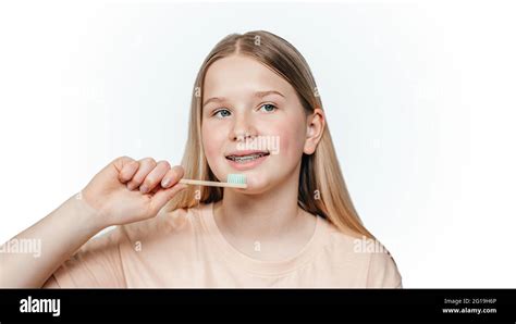 Smiling Blonde Girl With Orthodontic Braces Holding An Eco Friendly Bamboo Toothbrush