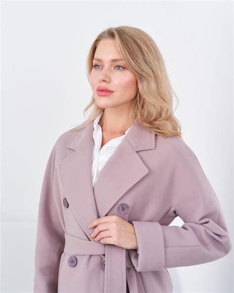 Beautiful Blonde Woman In A Stylish Coat Posing Cheerfully In A Bright Indoor Setting Stock