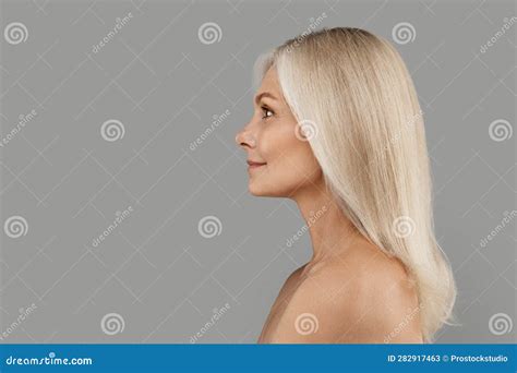 Profile Of Beautiful Mature Woman With Bare Shoulders Standing Over Grey Background Stock Image