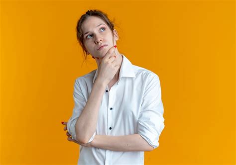 Jeune fille russe blonde réfléchie lève les yeux tenant le menton isolé