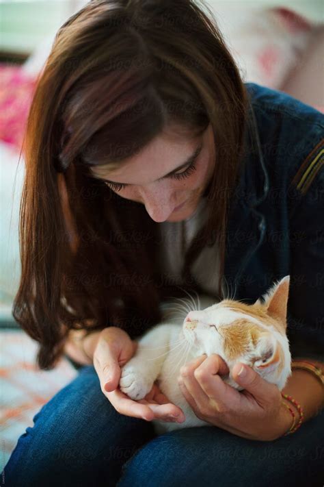 Long Haired Brunette Holding And Hugging A White And Ginger Cat Laying On Her Legs By Stocksy