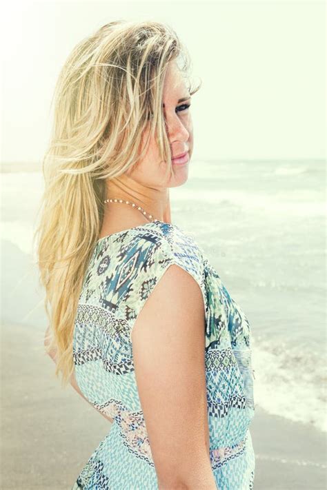 Fille Heureuse Blonde De Sourire En Mer Se Trouvant Sur La Plage Deux Mains Sous Son Visage