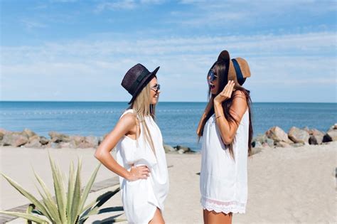 Deux jolies filles brune et blonde aux cheveux longs sont debout sur la plage près de la mer