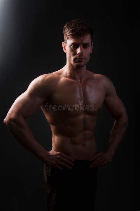 Muscular Bodybuilder Posing With A Naked Torso Against A Black Background Stock Photo Image