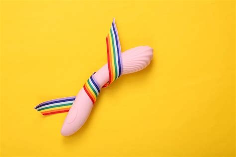 Premium Photo Sex Toy With LGBT Rainbow Ribbon Pride Tape Symbol On Yellow Background Top View
