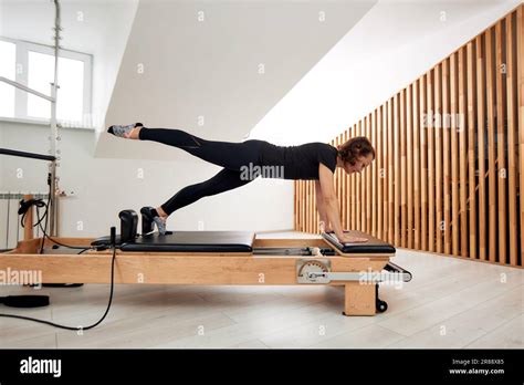 Une Femme Fait Pilates Sur Un Lit De Reformage Dans Un Studio Lumineux Une Brunette Souple