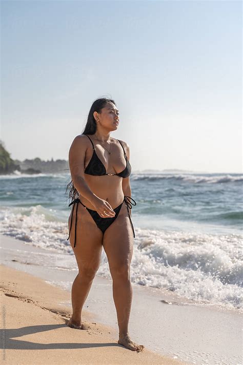 Curvy Woman Confidently Walking Down Beach In Bikini By Stocksy Contributor Jovo Jovanovic