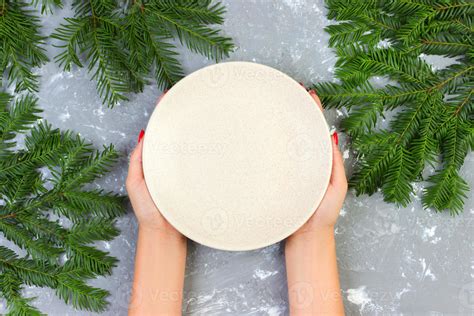 Female Hands Holding An Empty White Plate On A Gray Background With