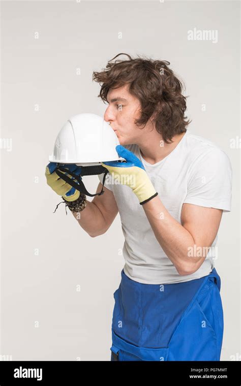 Portrait Of Funny Caucasian Male Builder Kissing Helmet On White