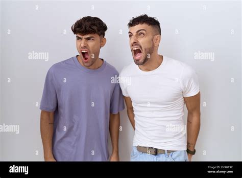 Homosexual Gay Couple Standing Over White Background Angry And Mad Screaming Frustrated And