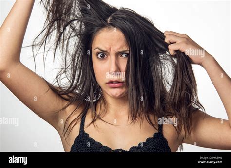Brunette teenager girl with anger expression pulling her messy hair ...