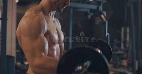 Handsome Strong Athletic Man With A Naked Torso Pumps Up Muscles On The Horizontal Bar In The