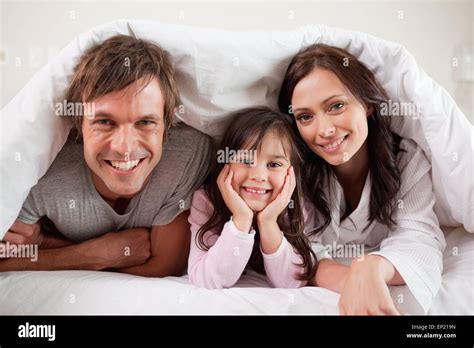 Parents Lying Under A Duvet With Their Daughter Stock Photo Alamy