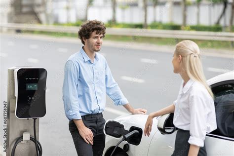 Progressive businessman and businesswoman with electric car parking and ...