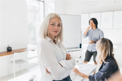 Fille Blonde Confiante En Chemisier Debout Avec Les Bras Croisés Au Bureau Avec Grand Flipchart