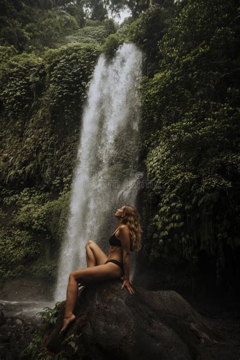 Una Niña Posa En Un Bikini En Una Cascada En Un Bosque Foto de archivo