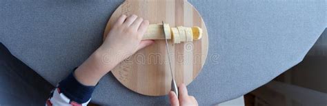 A 6 Year Old Child Cutting A Ripe Banana On Grey Background Stock Image