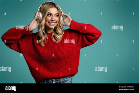 Portrait Of Charming Blonde Woman In Massive Headphones Listening To Music On Isolated Beige