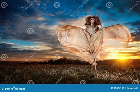 A Jovem Mulher Bonita Elegante No Nude Coloriu O Vestido Longo Que Gira Ao Redor A Vista Como