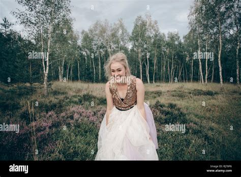 junge blonde Frau präsentiert Kleid inmitten von Besenheide Stock Photo Alamy