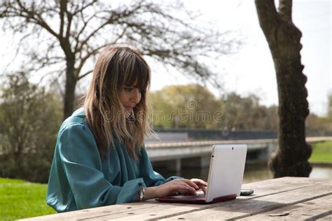 Jeune Belle Femme Blonde En Chemise Verte Assise Sur Un Banc En Bois Dans Un Parc Qui Travaille
