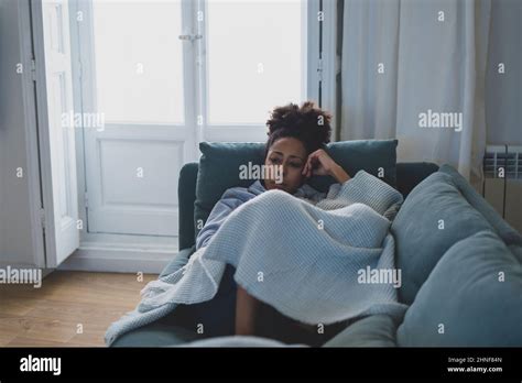 Einsame junge afro latina junge Frau auf dem Sofa Gefühl von Schmerz Erschöpfung und