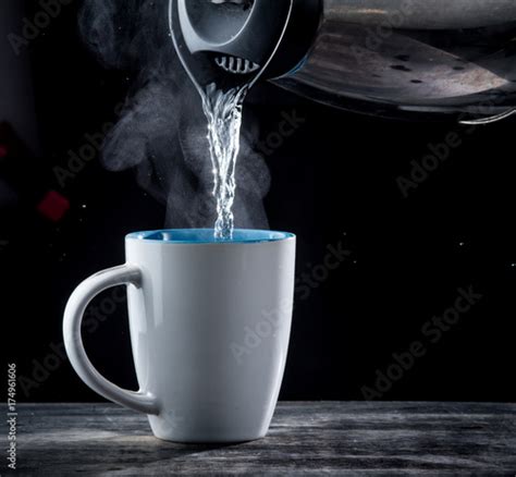 Pouring hot water into into a cup on a black background Stock Photo ...