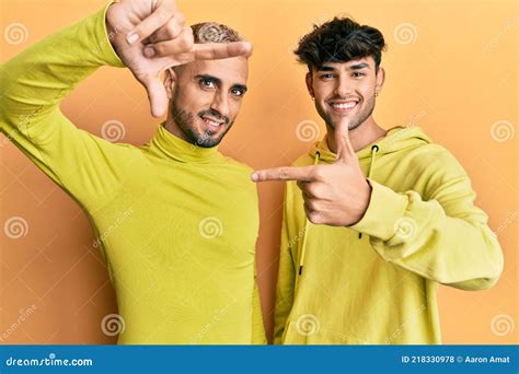 Homosexual Gay Pareja De Pie Juntos Usando Ropa Amarilla Sonriendo Haciendo Marco Con Manos Y