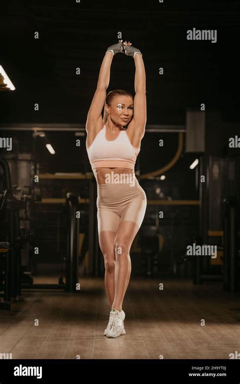 A Fit Woman With Blonde Hair Is Stretching With Her Hands Up In A Gym A Girl Is Relaxing After