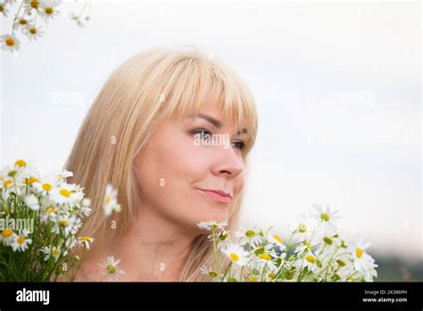 The Face Of A Plump Middle Aged Blonde Woman In Profile Against A Background Of Daisies Stock