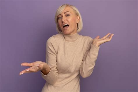 Confus Jolie Blonde Femme Slave Tient Les Mains Ouvertes Sur Violet Photo Gratuite