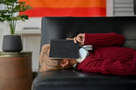 Premium Photo A Sleepy And Tired Asian Gay Man Covers His Face With A Book And Falling Asleep